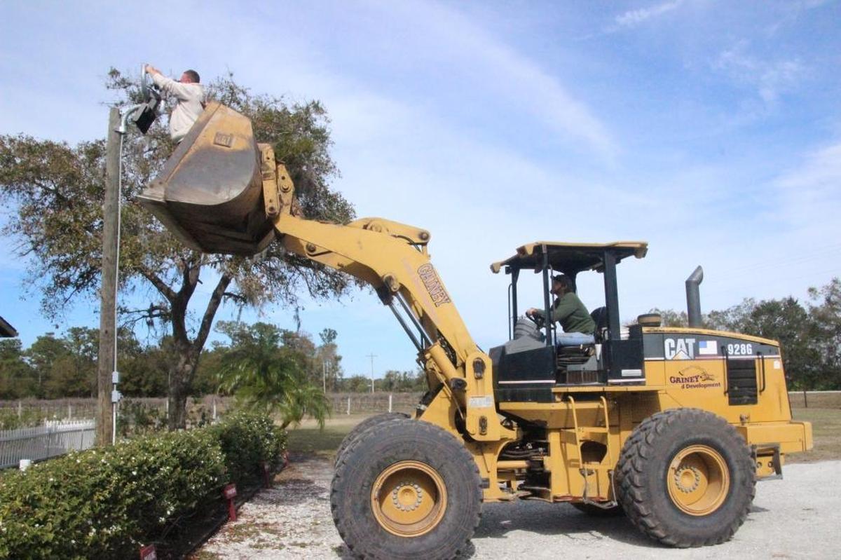Erik Hall pauses from his wine duties to repair a parking lot light at Fiorelli Winery. Hall and other small business owners find that being a jack of all trades comes in handy.