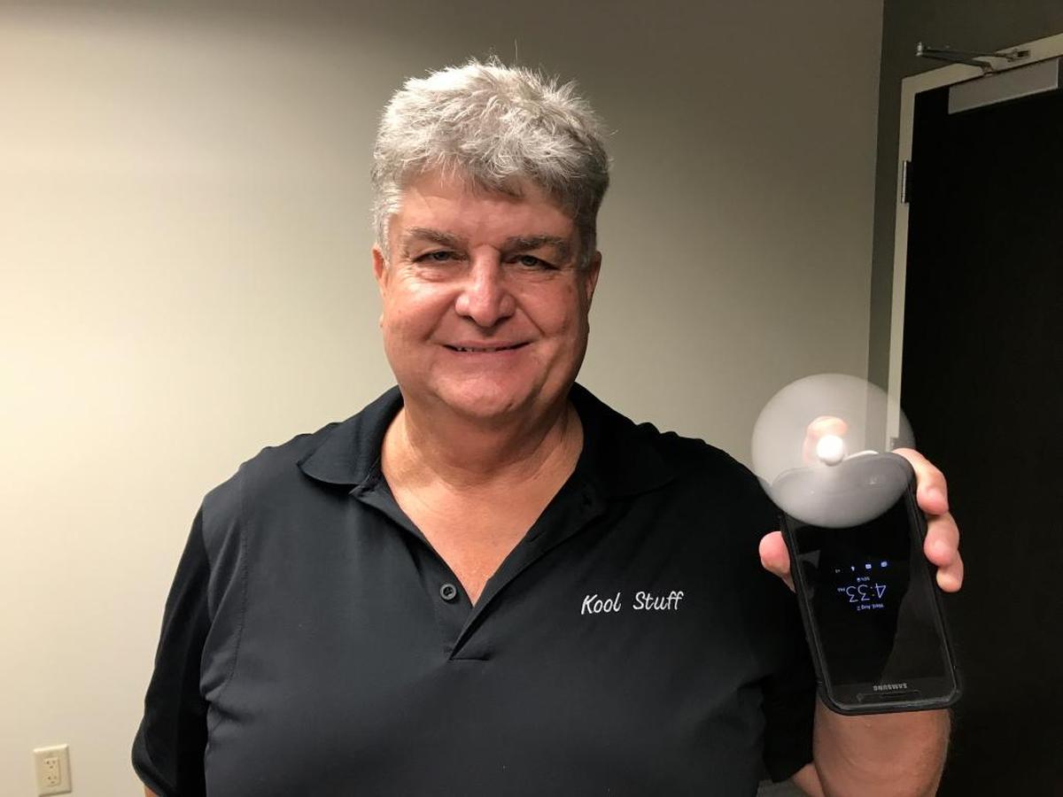 Tom Scholz demonstrates a portable fan that plugs into a smart phone.