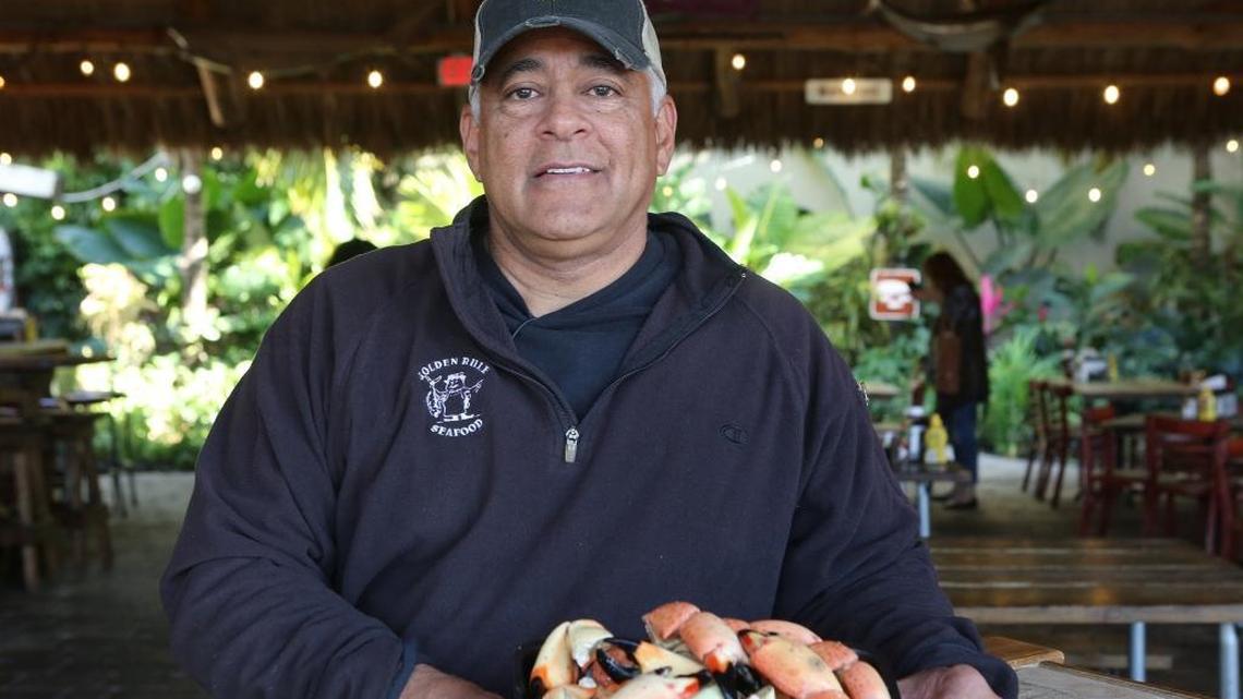 Walter Flores holds a plate of stone crab claws at Golden Rule Seafood in Palmetto Bay. A fire on July 4, 2022 destroyed the tiki hut in back of the market.