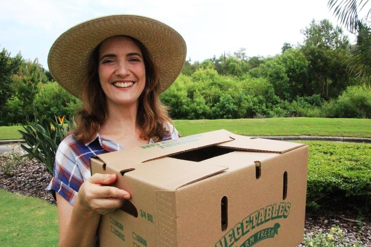 Eva Worden holds one of the three-quarter bushel boxes which will deliver organically grown produce to members December through April.