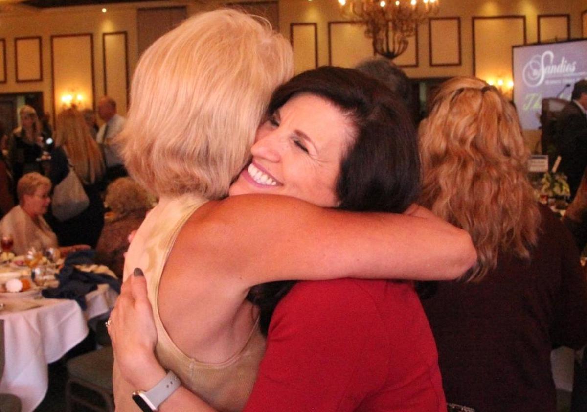 Viloleta Huseman, right, of Keiser University accepts a congratulatory hug from Kathy Herbst after being named volunteer of the year by the Lakewood Ranch Business Alliance on Friday.