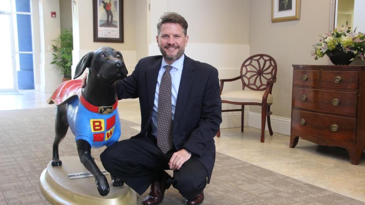 Jonathan Fleece, managing partner of Blalock Walters, P.A., is shown with a black lab statue from Southeastern Guide Dogs in recognition of the law firm’s support.