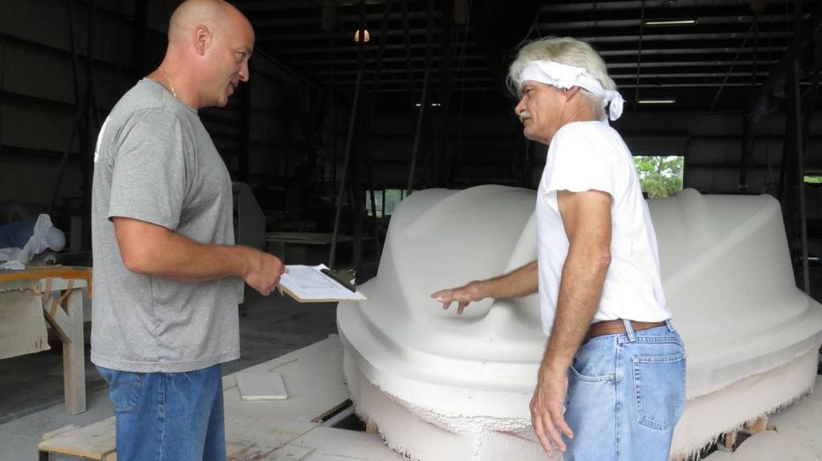 Hann Powerboats owner Russell Hann talks with employee Tony Clements about a hull under production at the company's Whitfield-area manufacturing facility. Hann Powerboats qualified for $118,000 in incentives for job creation, but has been unable to cash in on all the money due to fluctuations in its workforce.