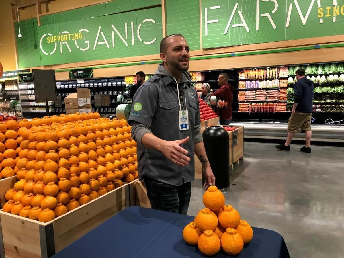 Steve Salsberry, standing by a neatly stacked display of sumo oranges, talks about Whole Food Markets’ produce during a tour this week. The new store at 5298 University Parkway opens Wednesday.