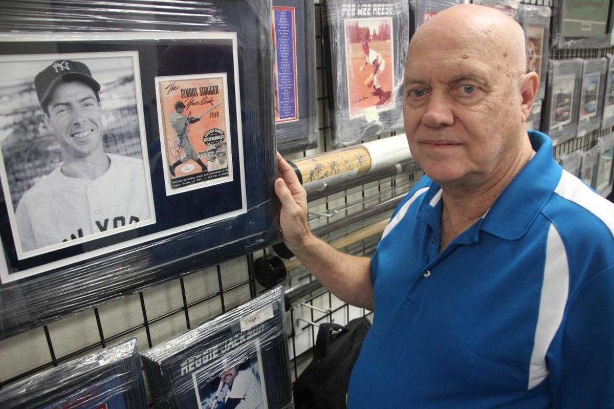 A signed Joe DiMaggio stat book is offered for sale along with his photo at D’s Cards & Memorabilia.