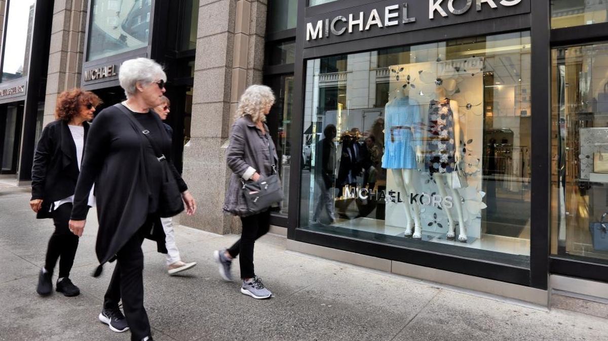People pass the Michael Kors store on Madison Avenue, in New York, Wednesday, May 31, 2017. Michael Kors Holdings plans to close up to 125 stores over the next two years with continued weak sales at its luxury stores.