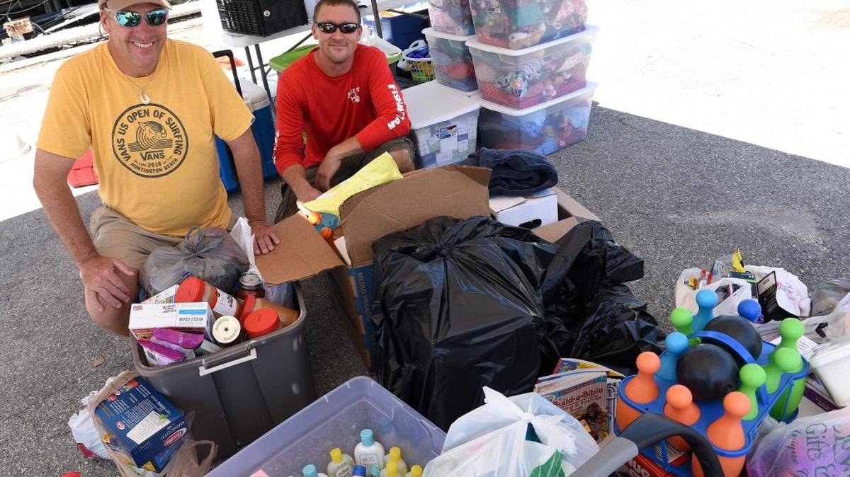 Bob Slicker and Brent Sudduth sit with supplies at Swordfish Grill and Tiki restaurant, which became the drop-off point for a community relief effort to benefit Hurricane Harvey victims. The restaurant is sending a trailer full of bottled water, clothing and other supplies to the affected areas in Texas.