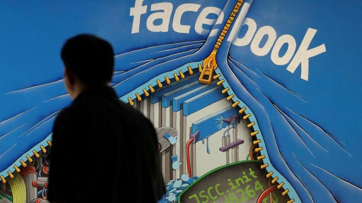 FILE - In this June 11, 2014, file photo, a man walks past a mural in an office on the Facebook campus in Menlo Park, Calif.