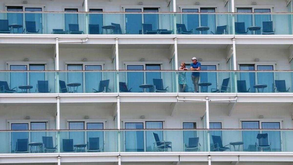 A pair of passengers aboard the Royal Caribbean International cruise ship Liberty of the Seas look from their balcony as other passengers disembark, Tuesday, Aug. 29, 2017, at PortMiami in Miami. The Galveston, Texas-based cruise ship was scheduled to return to the city Sunday but was diverted to Miami, because of Hurricane Harvey.