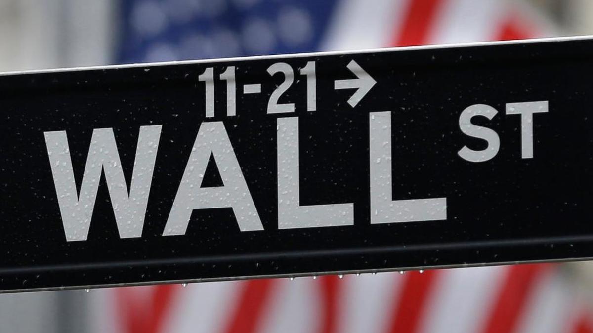 This file photo shows a Wall Street sign near the New York Stock Exchange in New York. Global stocks wavered Friday as investors looked to see if the three major U.S. indexes can add to their record close as well as upcoming retail sales figures.