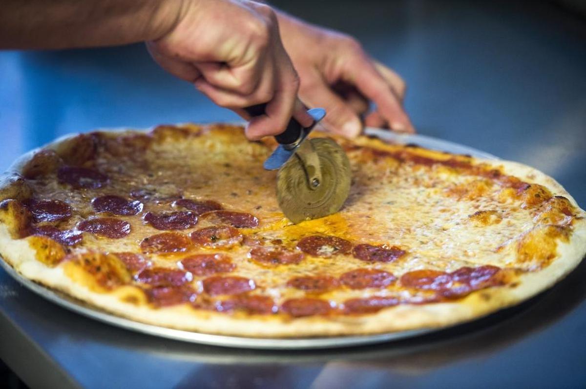 John Attardi cuts a freshly cooked pizza at Giovanni’s Brooklyn Pizzeria.