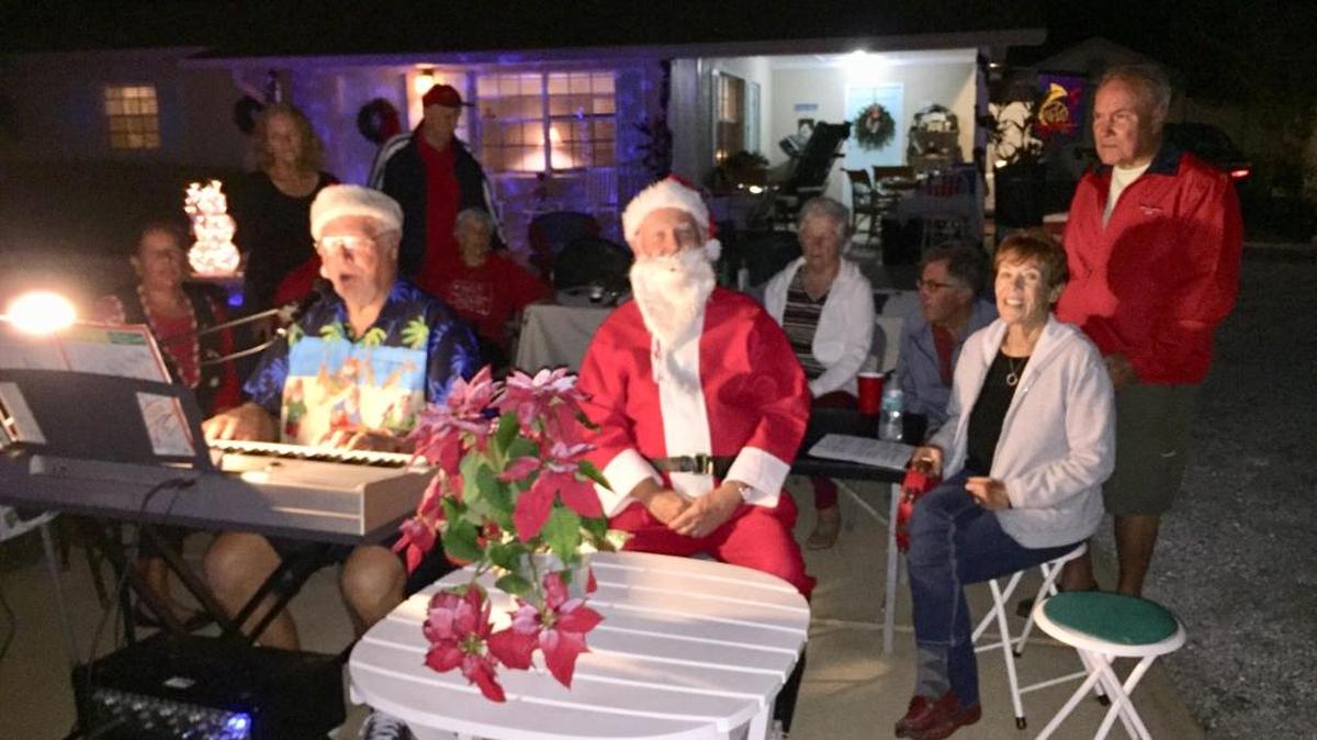 Paul Thibault, on keyboard at far left, leads The Palmetto 10th Street Tennis Pickup Group in a Christmas Carol. The group is putting on its “Live Christmas Caroling and Lighting Show” Monday and Friday evenings this week.