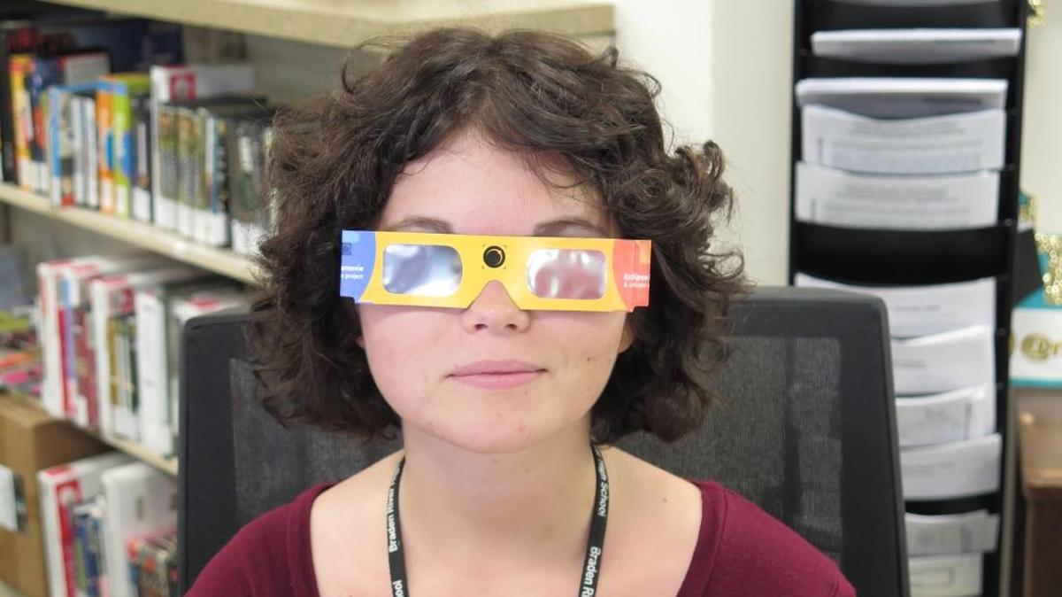 Shelby Hennessy, a Manatee County libraries intern, wears the Solar Eclipse glasses that are available at the county libraries. The county received the glasses from the Space Science Institute in Colorado.