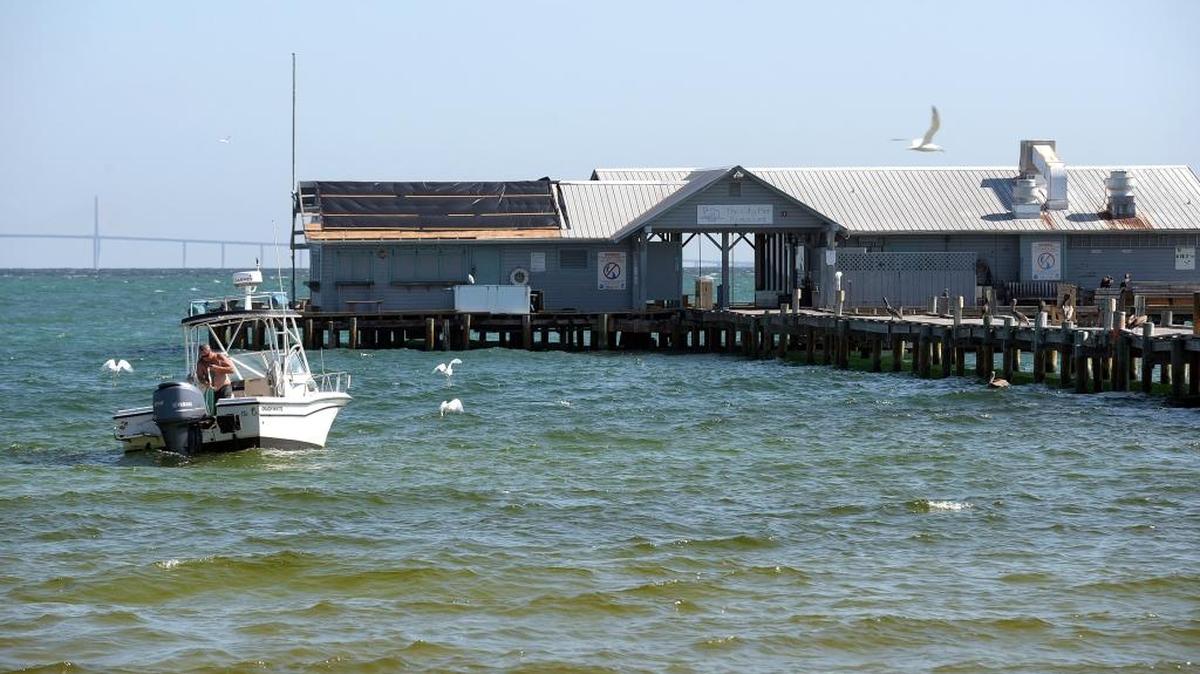 A fisherman sits in the waters off the Anna Maria City Pier, still closed from damage from Hurricane Irma.
