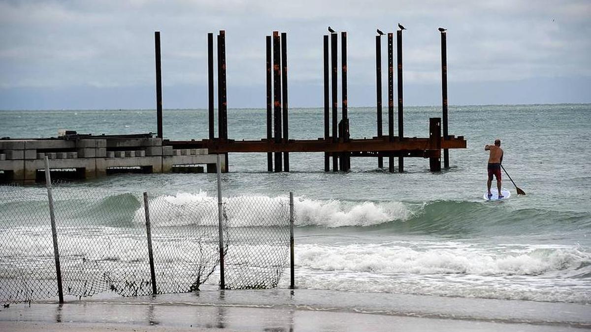 A paddleboarder slices through the waves near a groin under construction at Bradenton Beach during a break in the rainy weather in this file photo from May.