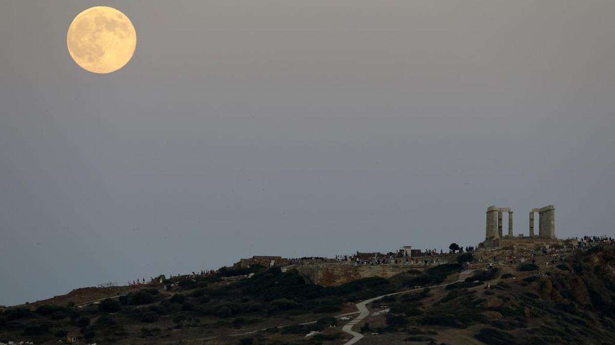 The moon appears above the ancient Temple of Poseidon as people watch it in Cape Sounio, about 68kms (42miles) south of Athens, Sunday, Aug. 10, 2014. The Super Moon phenomenon, which scientists call a "perigee moon," occurs when the moon is near the horizon and appears larger and brighter than other full moons.