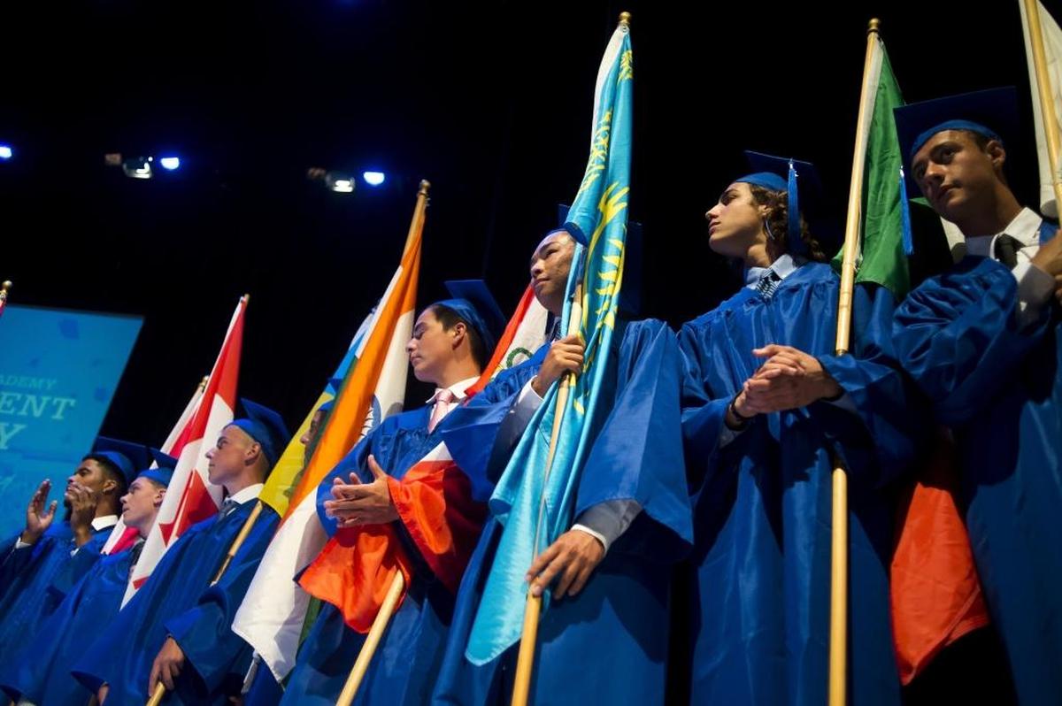 Graduates hold flags representing their country of origin before IMG Academy’s commencement ceremony in 2017 at the Van Wezel Performing Arts Hall in Sarasota.