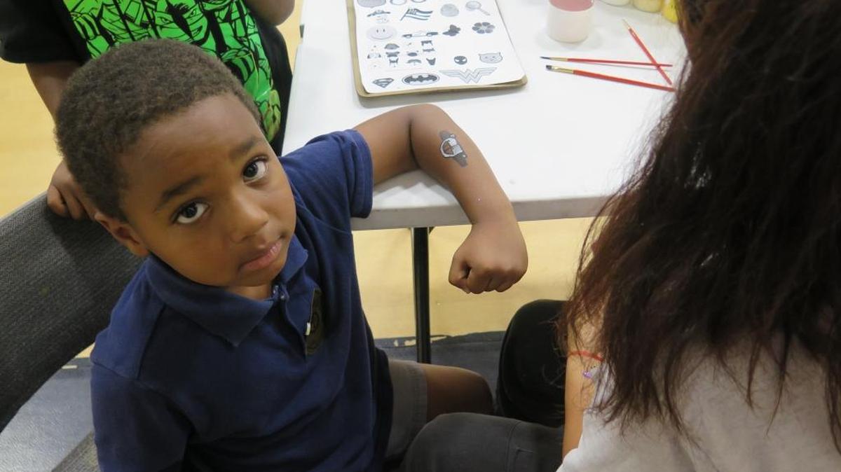 Brayden Carnegie, 6, looks up after having a police car painted on his arm Tuesday evening in Bradenton. Carnegie was one of several children who attended a National Night Out event in the 13th Ave Dream Center in Bradenton.