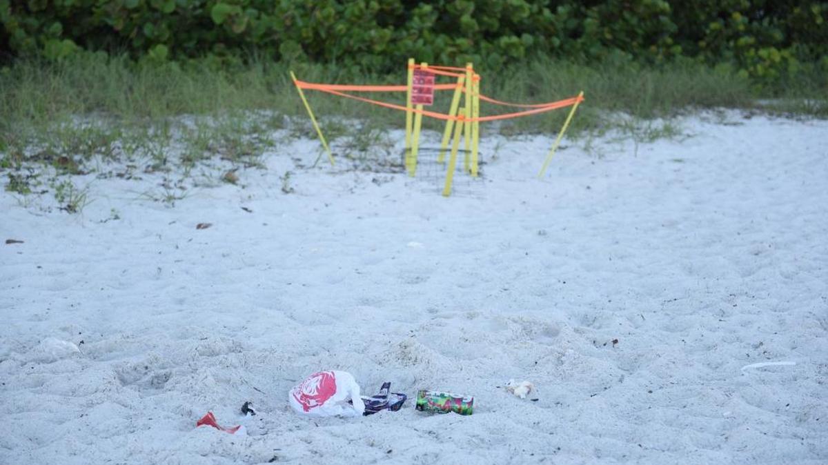 A pile of trash sits near a marked sea turtle nest on the morning after the Fourth of July on Coquina Beach.