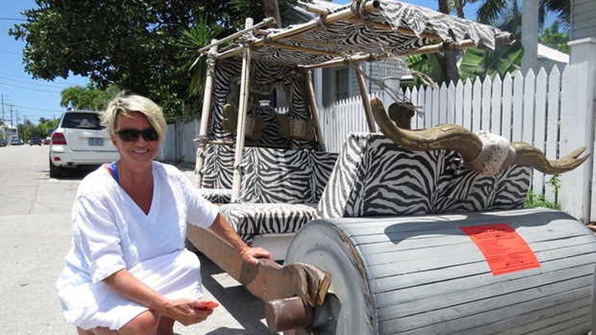 Carol Callowhill shows off this Flintstones-style, foot-powered car, a prop from a past Fantasy Fest parade. It was set to be removed Friday from a Key West corner where it sat for several months illegally 'parked,' city officials said. By then, it had moved from Emma Street to Duval.