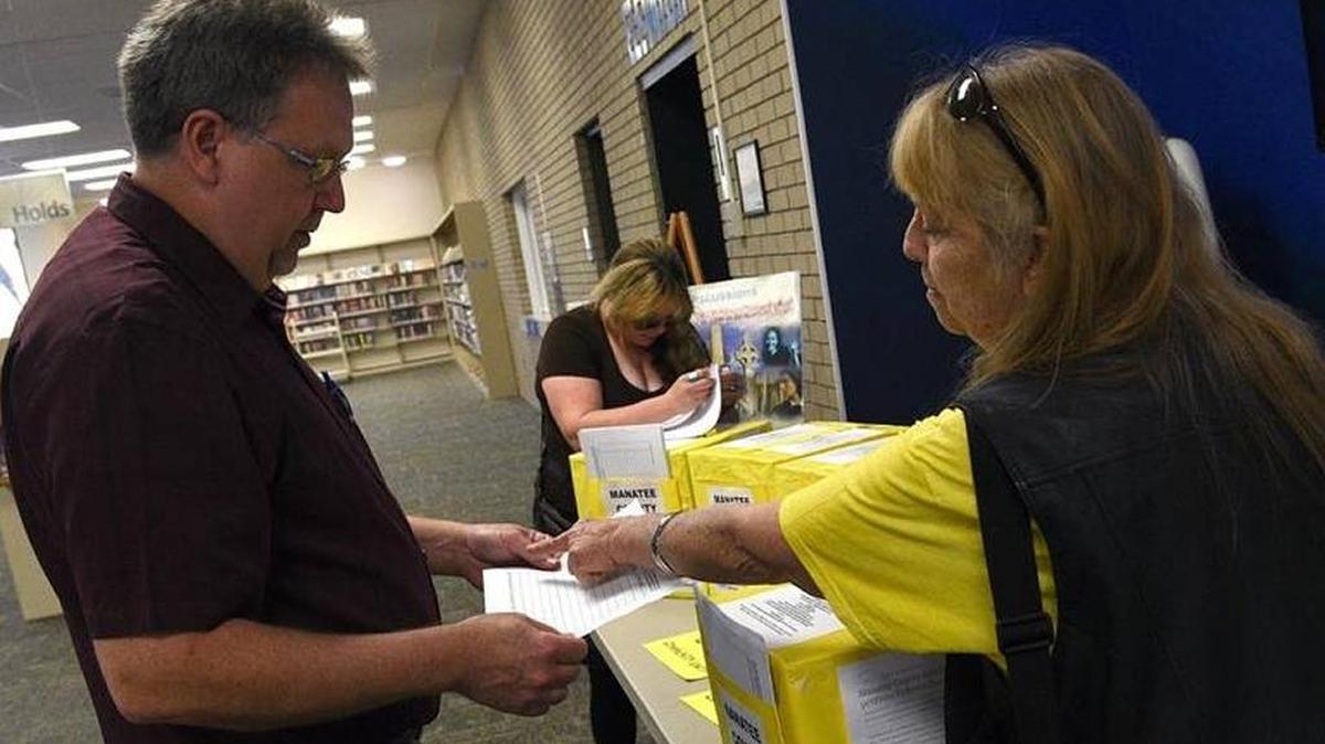 Kevin Beach, Manatee County library operations manager, with Barbara Elliott, with Stone Soup Community Unity Political Action Committee, in this file photo as Elliott drops off charter government petitions. The County Attorney’s Office ruled that such petitions are not allowed in the libraries on Wednesday.