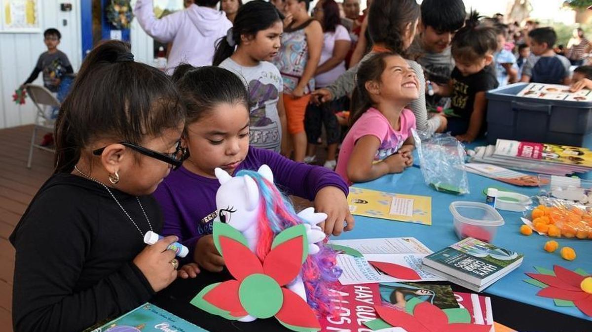 Children revel in the books and crafts at the public library table where the Farmworker Career Development Program of Manatee Technical College and the Adelante Team of Tropicana Products Inc. came together Tuesday to provide school supplies to more than 200 migrant children at the East Coast Migrant Head Start School.