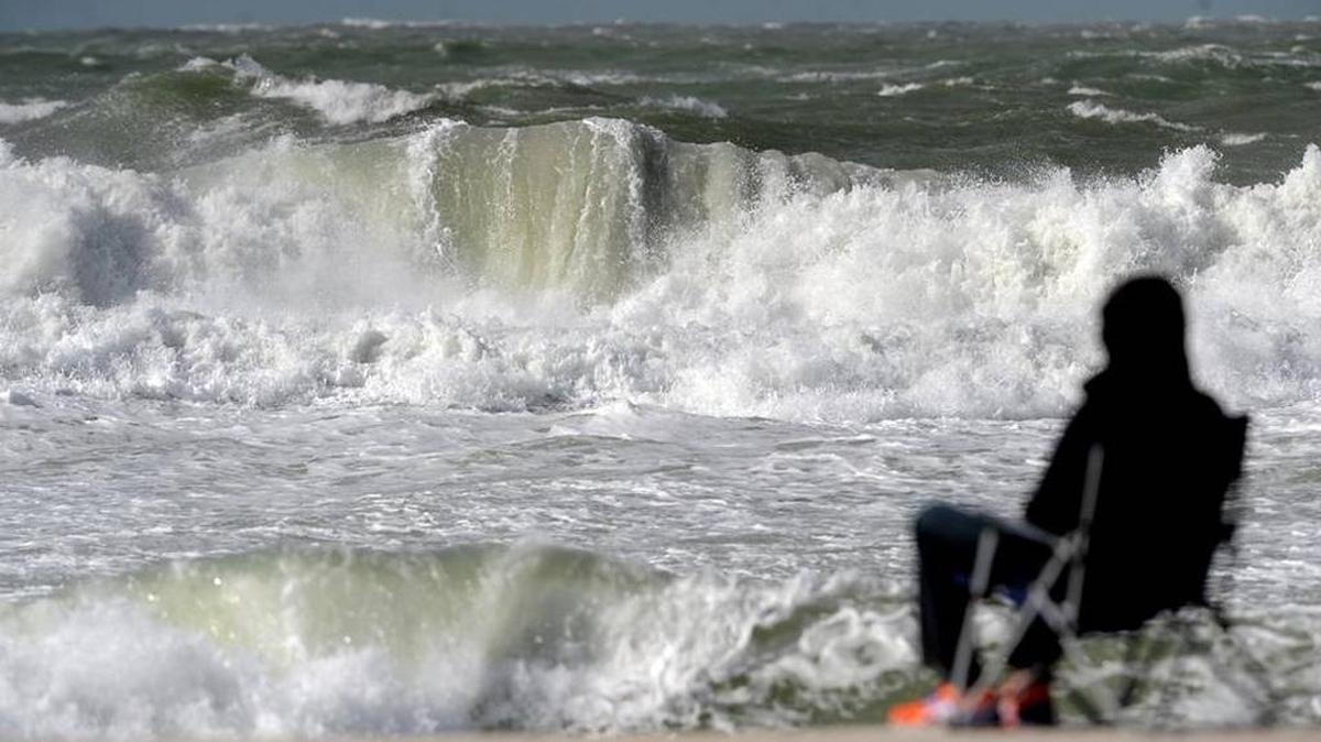 A man sits and watches the waves Saturday at Manatee Public Beach as high wind conditions stir up the surf in Jan. 2016.
