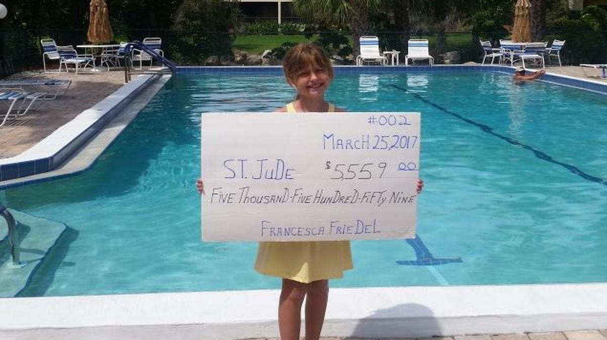 Francesca Friedel holds up a cardboard check showing how much money the 9-year-old raised for St. Jude Children’s Research Hospital in a recent fundraiser. Her chili/hot dog/lemonade stand raised more than $5,500 for the hospital.