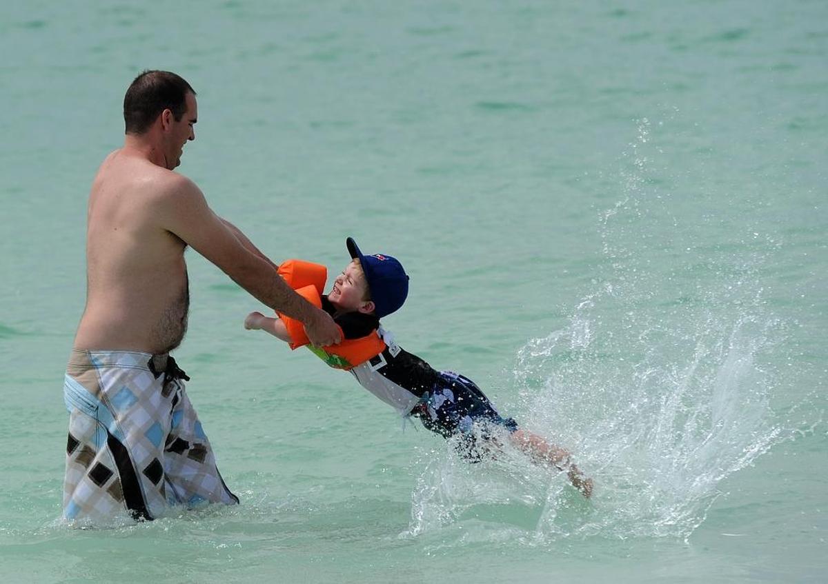 Jason Bakker swings around son, Callum, 4, in the waters of Manatee Public Beach.