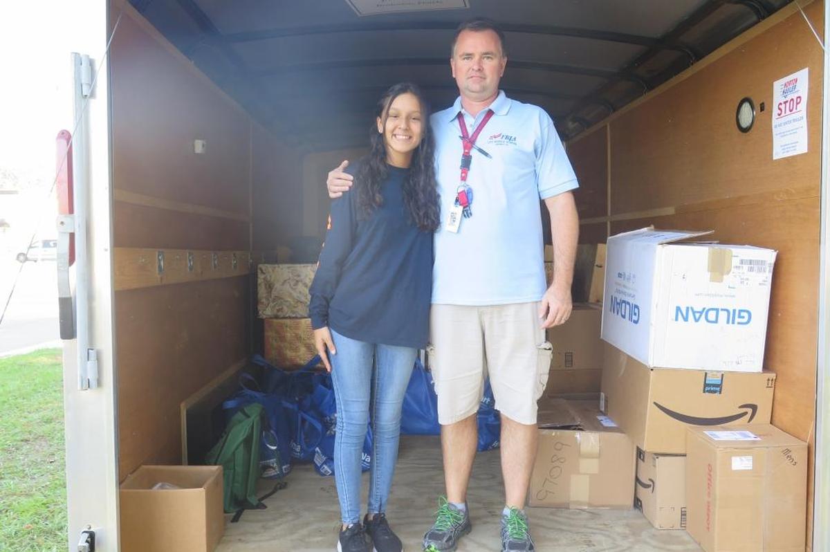 Yazmin Ramirez (left), and Lee Middle School business teacher Richard Daenell hand out presents to families and the homeless for the FBLA group’s second annual Blessing Basket event on Friday, Dec. 22.