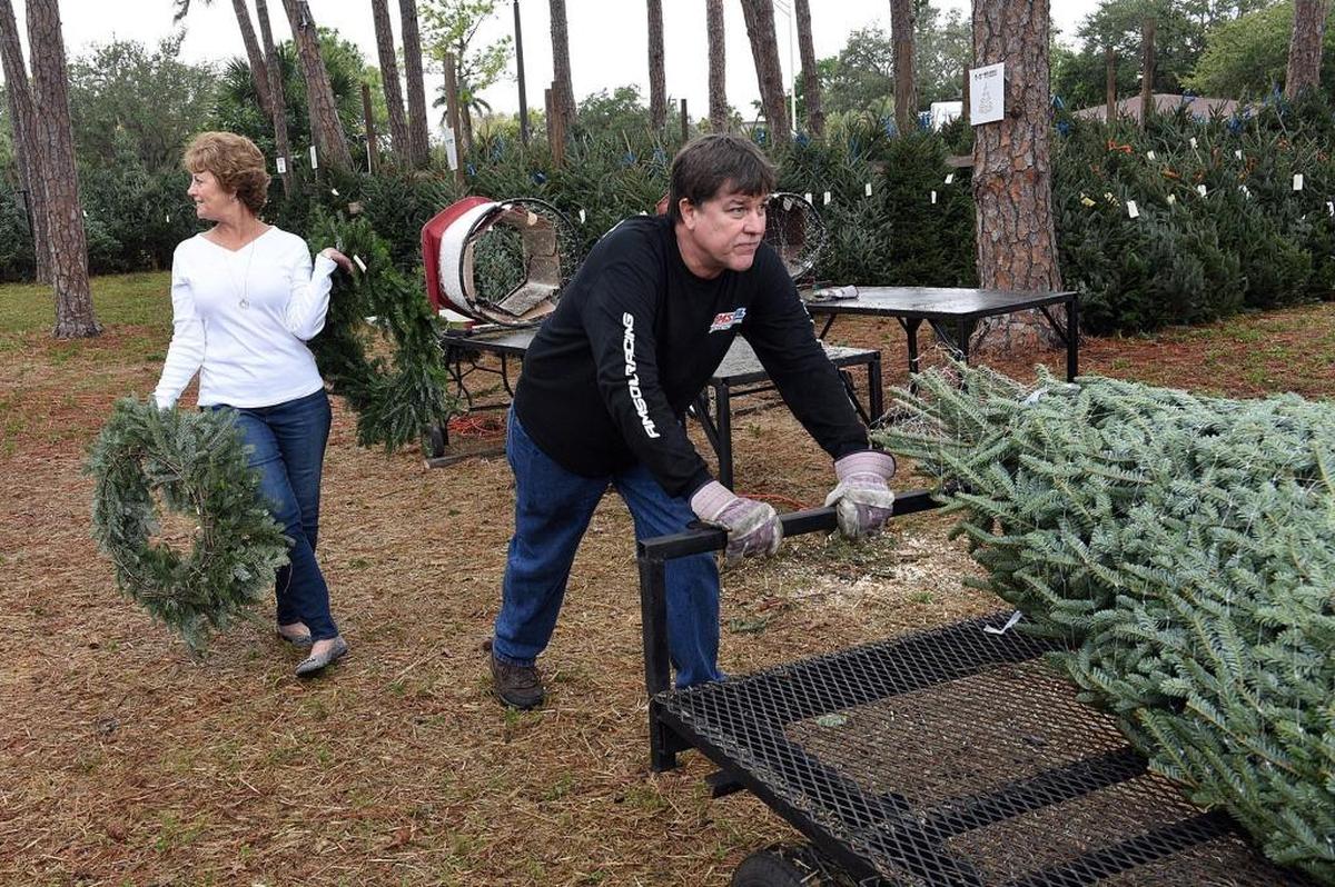 Debbie Steube carries two wreaths Friday as Jeff Gockley wheels the tree she chose from the Boys & Girls Clubs of Manatee County’s Christmas tree lot, a tradition since 1954 at McKelvey Park, 3913 Manatee Ave. W.
