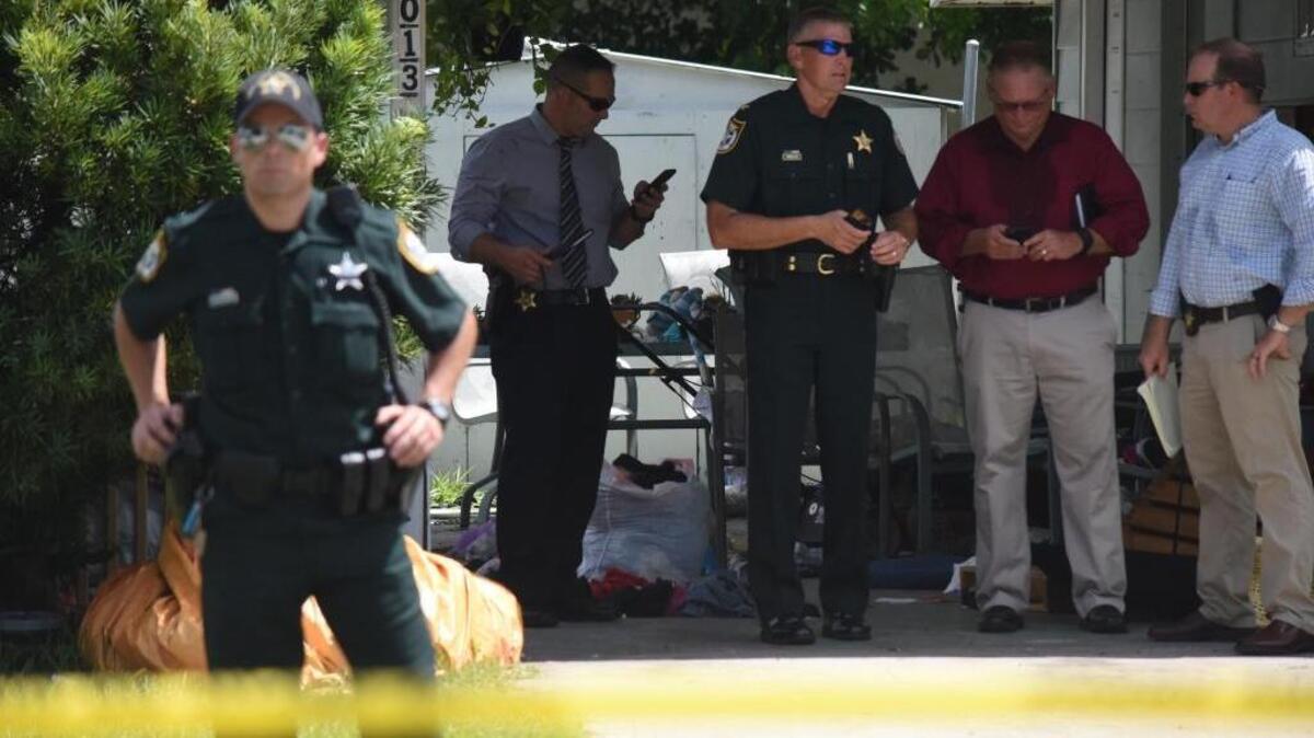 Investigators wait in the neighboring house of the crime scene in the 2000 block of 38th Avenue West during an investigation involving three dead Monday afternoon.