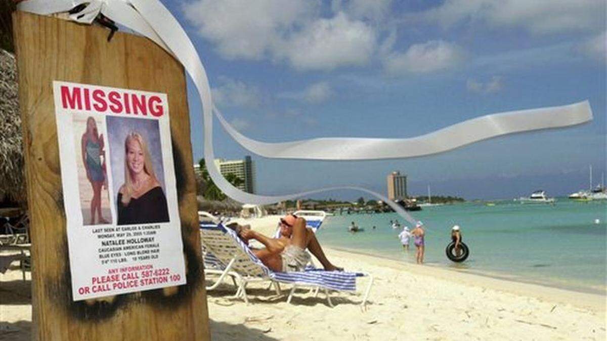 FILE - This June 10, 2005 file photo shows a missing poster for Natalee Holloway, a high school graduate of Mountain Brook, Alabama who disappeared while on a graduation trip to Aruba on May 30, 2005, on Palm Beach where tourists sunbathe in Aruba. Aruba prosecutors said Wednesday, May 20, 2015 a tip about the potential location of Holloway's body turned out to be false after spending weeks investigating the claim in the unsolved, decade-long disappearance of the U.S. teen.