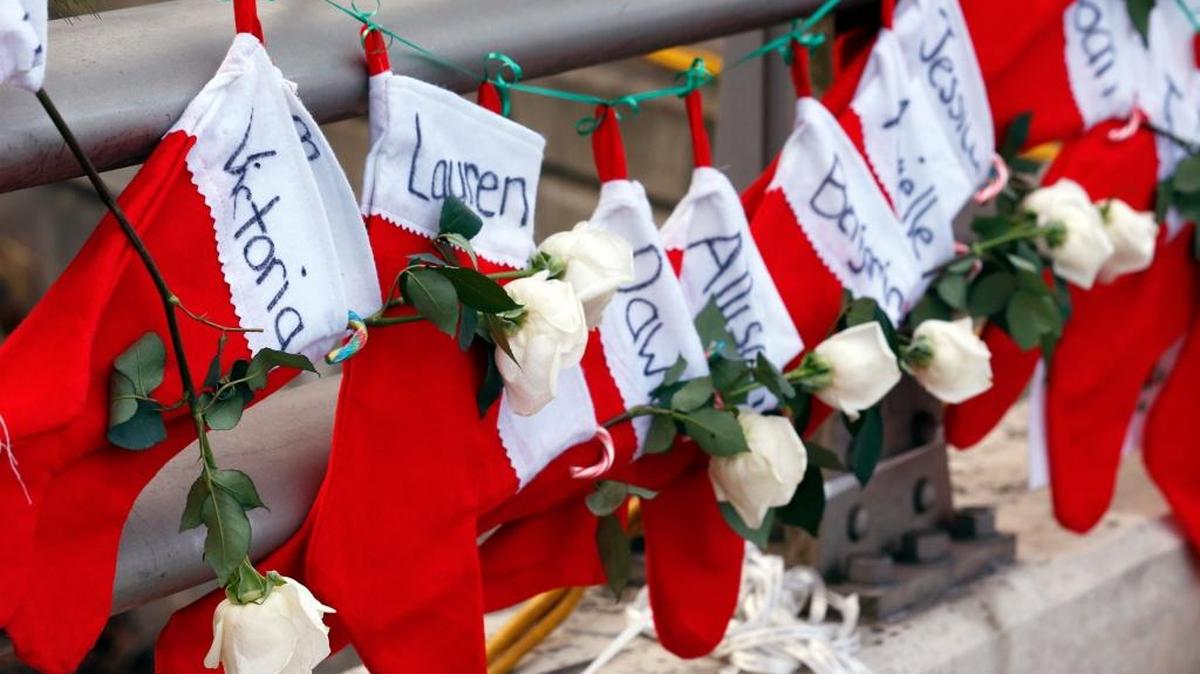 In this Dec. 19, 2012 file photo, Christmas stockings with the names of shooting victims hang from railing near a makeshift memorial near the town Christmas tree in the Sandy Hook village of Newtown, Conn. In the wake of the shooting, the grieving town was trying to find meaning in Christmas.