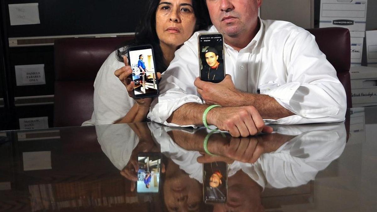 The parents of Sebastian Gregory — Amalia Villafane, left, and Andres Gregory, right. Their son committed suicide in 2016 after being shot six times by a Miami-Dade police officer, They are holding photos of Sebastian in the office of their attorney, who has sued the county over what the family argues was excessive use of force by the officer.