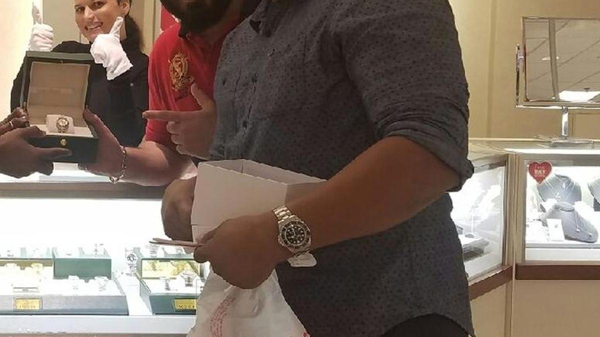 Identity theft suspects pose with the Rolex they purchased, police say, with fraudulent credit.