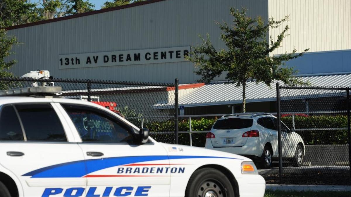 A Bradenton police officer stands watch outside of the parking lot of 13th AV Dream Center where Brenton Coleman Sr. was killed by gunmen at the end of a youth football practice in this 2013 file photograph. FILE PHOTO