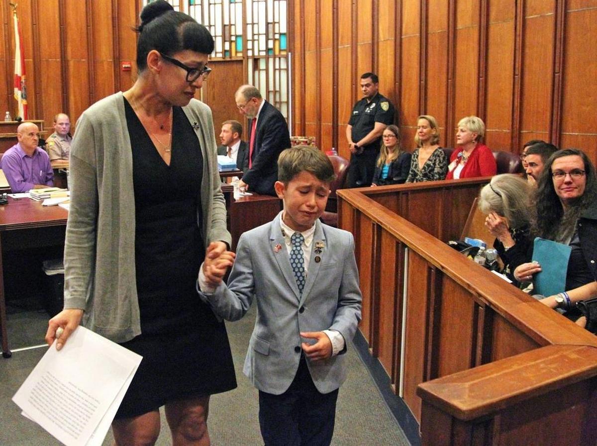Suzy Rivera, left, and her son, Patrick McGuire, 7, walk hand-in-hand after they testified about their loss.