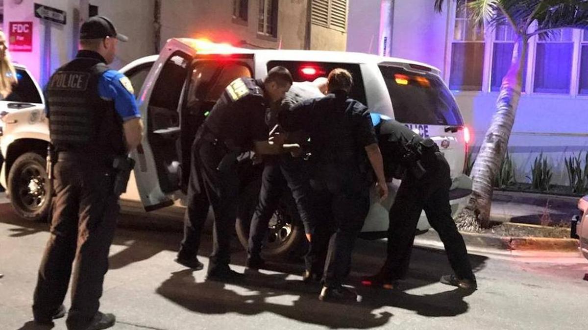 Authorities handcuff Enrique Antonio Gamez and load him into the back of a Homeland Security SUV.