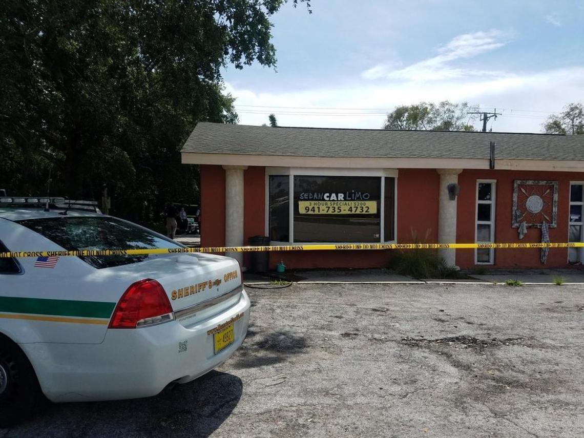 The body of a homicide victim is shielded from view Thursday afternoon in the back parking lot of a business in the 7400 block of Tamiami Trail.