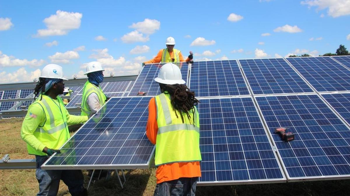 File photo: Workers move a solar panel into place at FPL's Manatee Solar Energy Center.