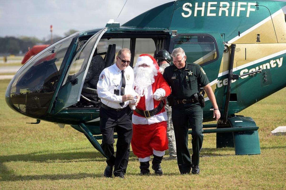 William Quinn and Sheriff Rick Wells escort Santa after he arrived by helicopter at the annual Flight to the North Pole Christmas celebration for children with illnesses, hosted by the Manatee County Sheriff's Office, Thursday at the Sarasota/Bradenton Airport Fire Station.