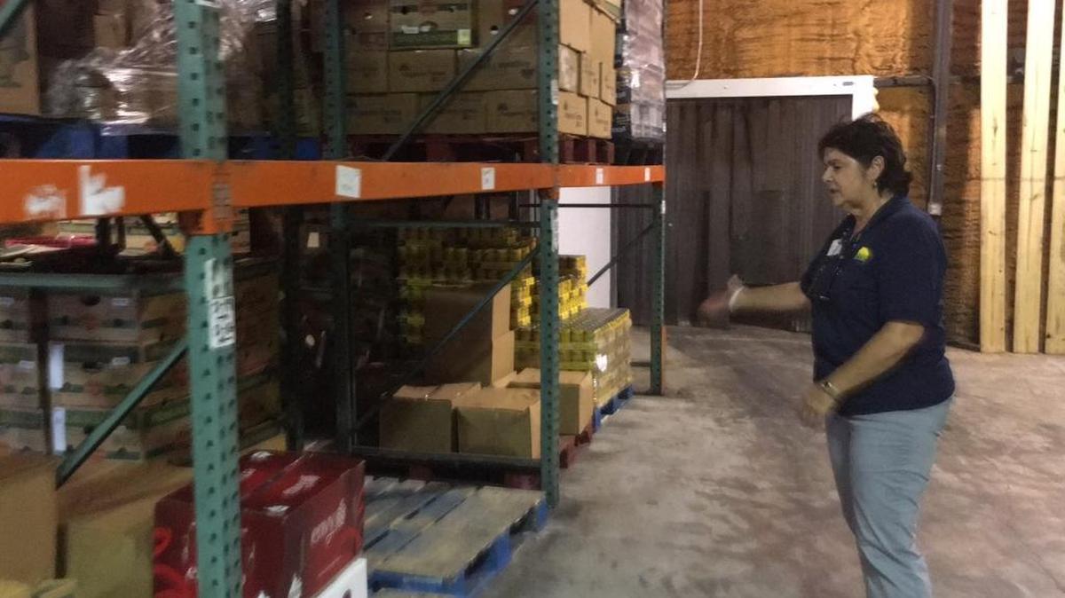 Cindy Sloan of The Food Bank of Manatee points out the dearth of food on some of the shelves at food bank on Monday. Sloan hopes that the Aug. 28 "Stuff The Bus" food drive will replenish the bank, which often gets depleted during the summer.