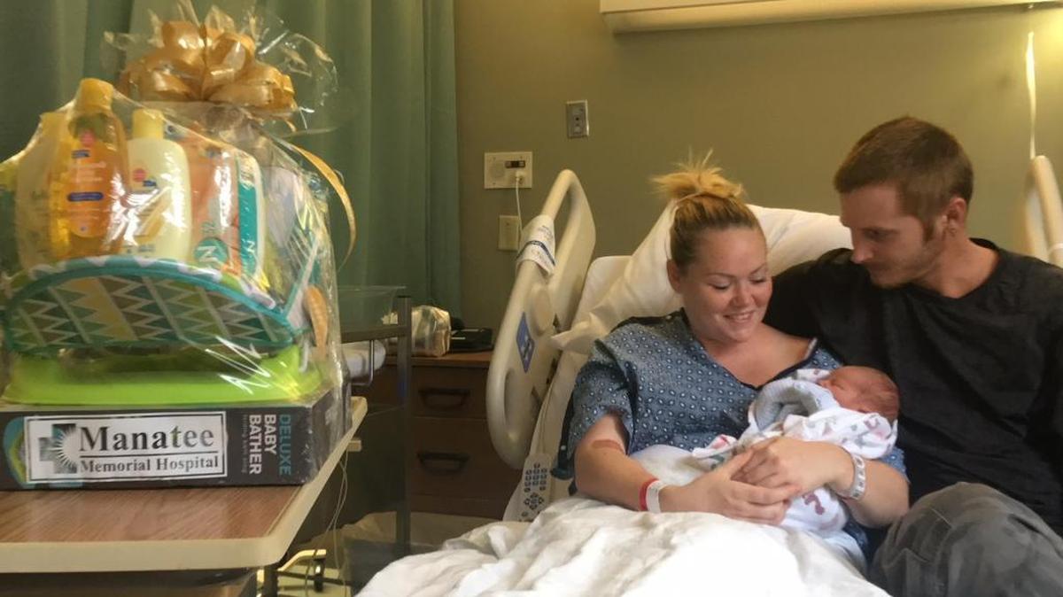 Emily Baker, left, holds her son Kiah Casseus, the first baby born in Manatee County in 2018. Baker, who was joined at Manatee Memorial Hospital by her boyfriend, Erik Ramsey, right, received a blue basket of gifts, left, from the hospital.