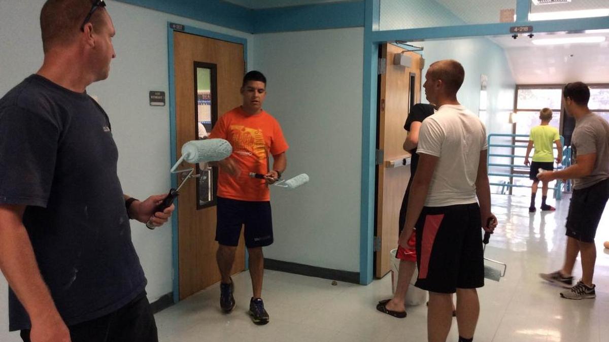 Members of the U.S. Coast Guard help paint the fourth- and fifth-grade hallway at Oneco Elementary School.