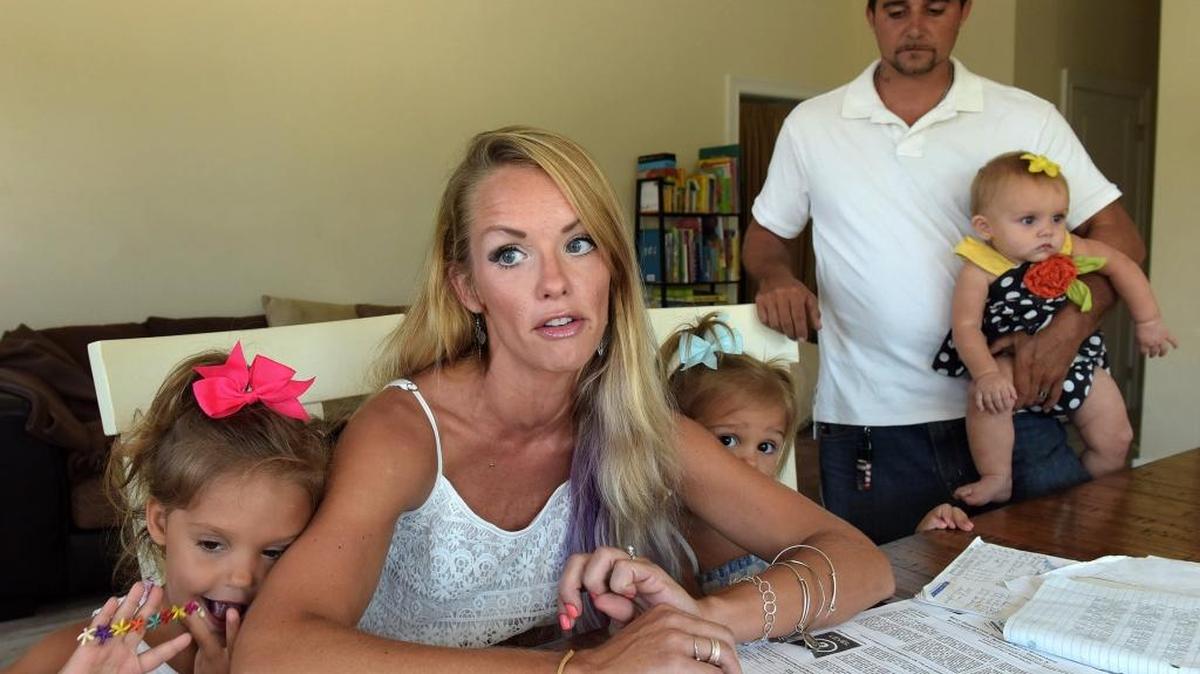 Samantha Martin and Nick Kimon want their child (not pictured) to be retained and to repeat a grade because her report cards filled out by teachers and her state test grades indicate she's not academically ready to move on. But every year, she's promoted. Here they sit in their living room with other children Maizy, 3, Danika, 2, and Valynn, 9 mos.