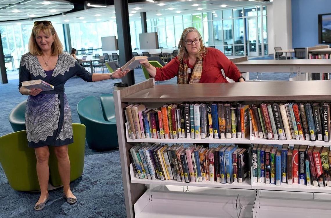 State College of Florida's president, Carol Probstfeld passes a book to library director Meg Hawkins at State College of Florida's book brigade event Monday.