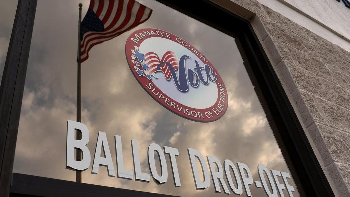 The flag flies in the reflection of the window of the Supervisor of Election’s office.