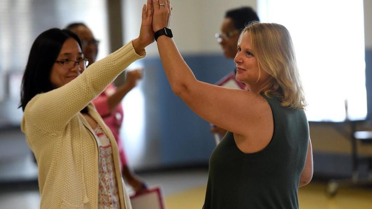Jadah Hodge and Tracie Kilty give high fives as staff at Rogers Garden-Bullock Elementary School participate in training. The district closed down Orange Ridge this year and moved the bulk of those students to Rogers Garden because Rogers Garden was failing to attract students.