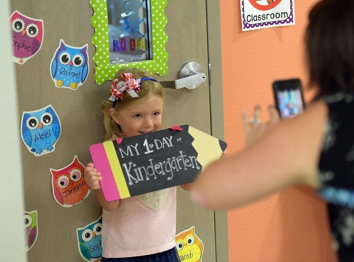 Emily MacFarlane, 5, holds up a sign for a photo for her mother on the first day of school at Jessie P. Miller in Bradenton Thursday.